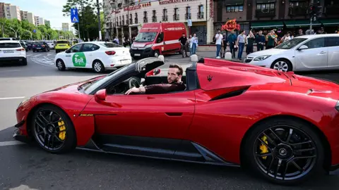 Getty Images Tristan Tate driving a red sports car in Bucharest, 2024