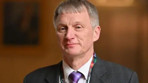 Getty Images Ivan McKee head and shoulders wearing a purple tie and a lanyard