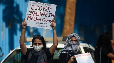 Getty Images Activists hold placards during a protest to condemn the alleged gang rape and murder of a 19-year-old woman in Bool Garhi village of Uttar Pradesh state, in Mumbai on October 6, 2020.