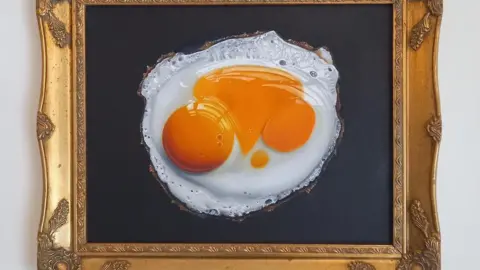 Daniel Halksworth A framed picture of a double yolker on black canvas.