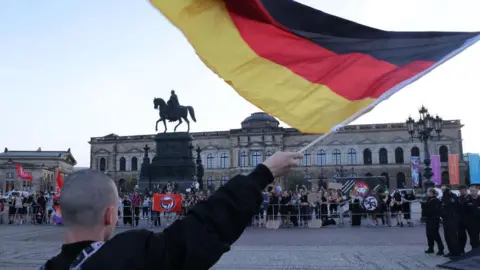 Getty Images A man holds a German flag at a protest in Dresden