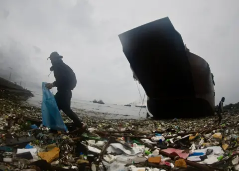 France R Malasig / EPA-EFE A villager collects recyclable materials next to a ship that ran aground at Manila Bay, Philippines