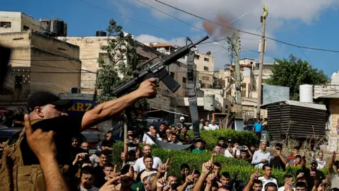 Reuters A Palestinian gunman fires into the air during the funeral for four Palestinians killed by Israeli forces, in Tubas, in the occupied West Bank (5 September 2024)