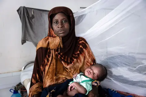  Alyona Synenko/ICRC A mother cradles her baby in her arms at a Red Cross hunger clinic in the Somali city, Kismayo