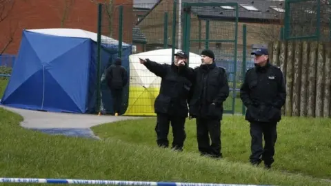 PA Media Three police officers in a play area in Rochdale