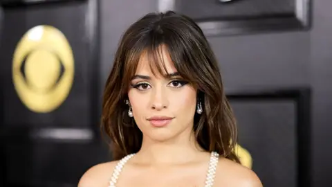 Getty Images Camila Cabello at the 2023 Grammy awards, in front of a black board with the golden logo of the grammys