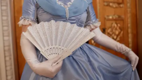 Getty Images Close up of lady wearing blue ballgown curtsying