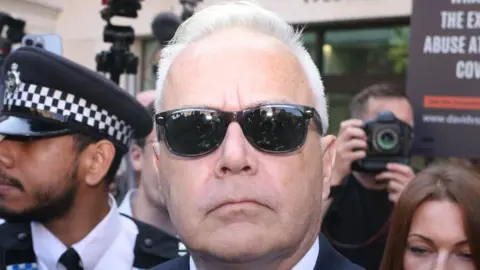 Getty Images Huw Edwards, wearing sunglasses, outside court during his first appearance in July