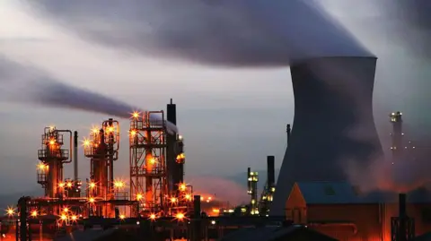 Getty Images Grangemouth at dusk with chimneys and industrial towers lit by orange lights