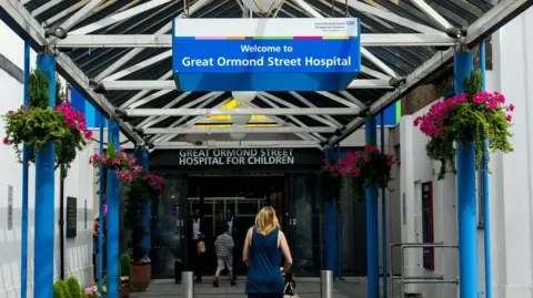 EPA A woman walks under a sign for Great Ormond Street Hospital in its entrance. 