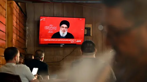 EPA People watch Hezbollah leader Hassan Nasrallah delivering a televised speech at a coffee shop in the southern suburbs of Beirut, Lebanon (19 September 2024)