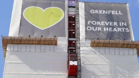 PA Grenfell Tower in west London with a sign on the top of the building, reading: "Grenfell forever in our hearts"