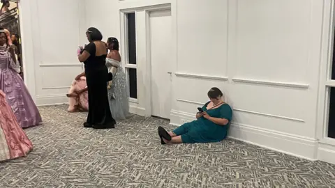 @moreofnita Women dressed in their finest outfits sitting on the floor scrolling on their phones