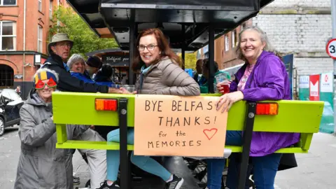 Pacemaker Passengers of the cruise ship smiling on a beer bike in Belfast with a sign that says 'Bye Belfast, thanks for the memories'