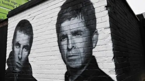 Getty Images A black and white mural on a brick wall depicting Liam Gallagher (L) and Noel Gallagher (R) 