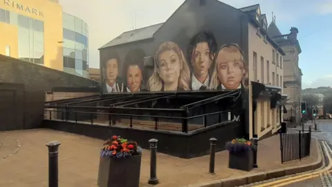 BBC An image of the Derry Girls mural now obstructed by a new awning installed on a pub in the city centre. 