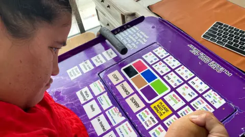 Marlena uses a purple board with words and colours on it to show what she means