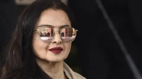 Getty Images Rekha poses for photographers in Mumbai