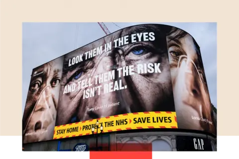 Getty Images At Piccadilly Circus the giant advertising screen show the faces of coronavirus patients, and a slogan which says 'look them in the eyes and tell them the risk isn't real'. It also reads 'Stay home protect the NHS save lives'