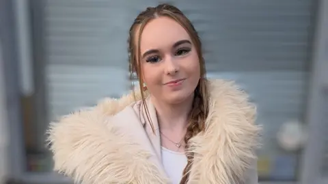 Tiegan Moseley wearing a white fluffy coat. Her hair is tied in a braid