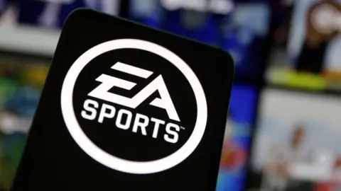 Reuters A black sign with the logo of EA Sports in white on it stands in front of a number of blurred screens