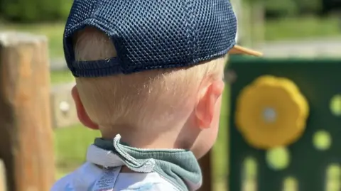 Family photo A little boy with blonde hair in a cap looking into the distance