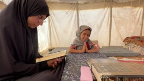 Insaf reads from the Quran with her daughter Saba