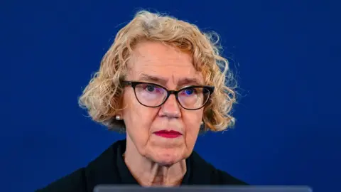 PA Media Chair of the inquiry Lady Justice Thirlwall at Liverpool Town Hall. She has cropped curly blonde hair and wears dark coloured glasses. She is wearing dark coloured, smart clothing. 