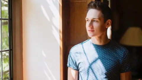 James, standing in front of a window in sunlight