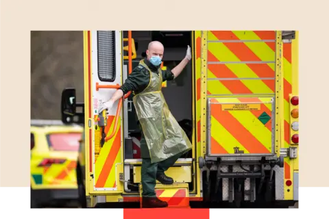 Getty Images An ambulance worker in the back of an ambulance outside a hospital, wearing a mask.