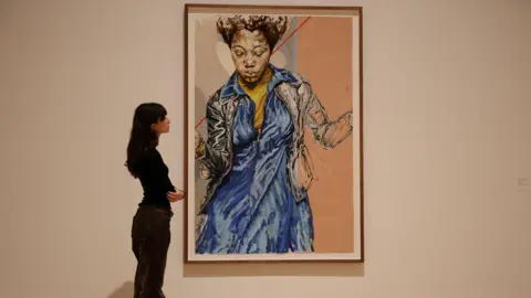 EPA Gallery assistant posing alongside a Claudette Johnson portrait of a black woman in a blue dress at Tate Britain