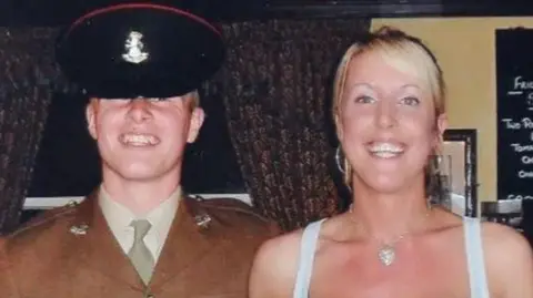 Angie Moore Pte Stone, wearing a ceremonial, dark green Army dress uniform and cap, with his sister Jennie, who is blonde haired and wearing a white vest top.