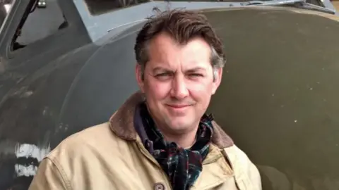 World War Two writer, broadcaster and historian James Holland pictured in front of a plane.