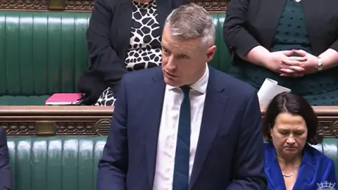 ParliamentLive.TV Luke Pollard wears a white shirt, blue tie and blue jacket and is standing at the despatch box