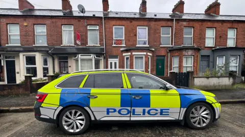 Pacemaker A police car parked outside a row of red brick terrace houses in Belfast