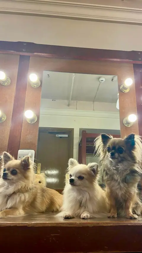 Bridget, daughter Charlotte and granddaughter Rita backstage at the Theatre Royal in Glasgow. They are sitting in front of a mirror.