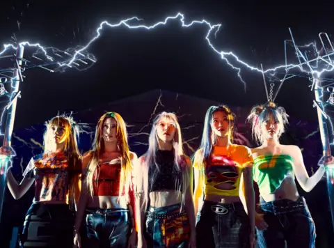 Source Music Le Sserafim are surrounded by bolts of lightning and sparks of electricity in a promotional photo supplied by their record label