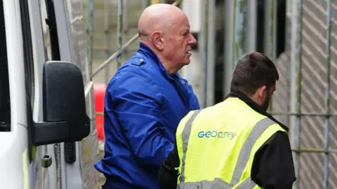 AP Neil foden being led from a prison van into court