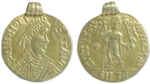 Andrew Williams/Norfolk County Council Gold Anglo-Saxon Roman-style pendant, showing a fairly crude image of an Emperor with writing around it on the front and a back view of a figure holding a banner, also with writing around it