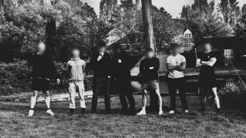 Telegram Seven members of Active Club North West pose in sportswear with their arms crossed in a rural setting for a group black and white photograph 