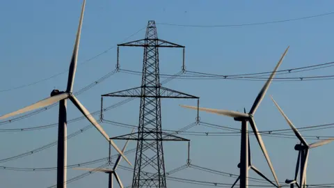 PA Wind turbines with an electricity pylon against a clear blue sky