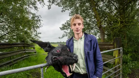 FremantleMedia Ltd/Naked West  Charlie Cooper with a costume head of the Black Shuck, a ghostly dog that roams East Anglia 