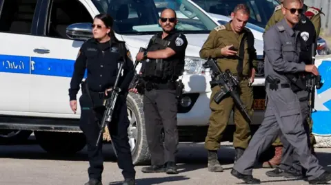 Reuters Israeli security personnel standing in front of a vehicle (file photo)