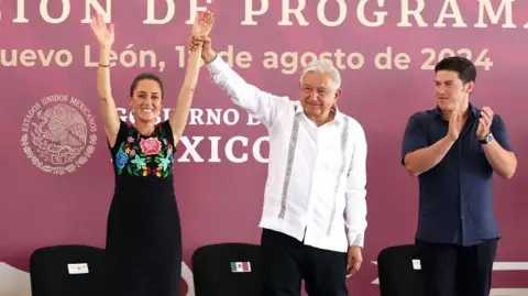 Getty Images Andrés Manuel López Obrador holding up Claudia Sheumbaum's arms at an event back in August