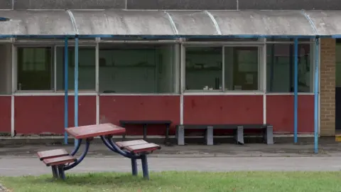 BBC/ Gemma Laister A lopsided picnic bench on a patch of grass outside one of the buildings at Patchway Community School, thought to have been constructed in the 1950s.