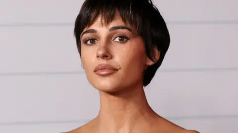 Reuters Naomi Scott looks at the camera. She has short dark hair, brown eyes and wears neutral makeup.