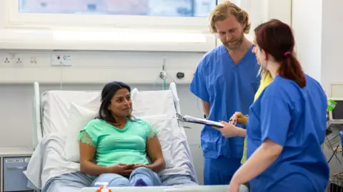 Getty Images Health workers talking to a patient 