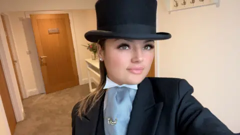 Hollie James A selfie of a young woman dressed in black funeral attire with black top hat on 