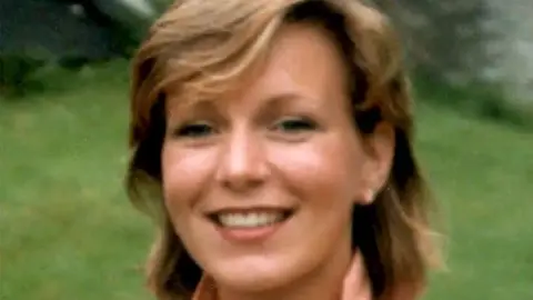 A woman with short brown hair smiles into camera