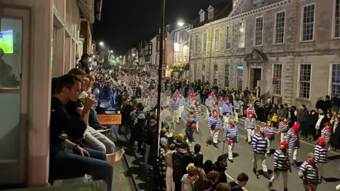 George Carden Spectators perched on a window sill looking out over Lewes Bonfire procession in High Street, Lewes